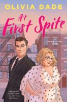 Cover of At First Spite. Man and woman standing in profile, backs/sides barely touching. Man is wearing black suit and has one eyebrow raised. Woman is wearing flowy wrap dress, glasses and is smiling slightly.